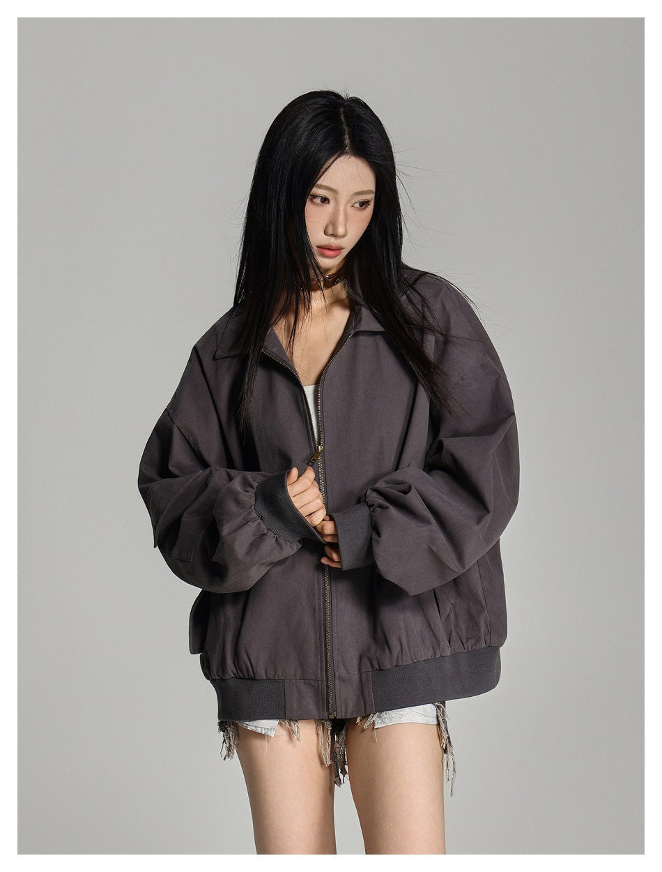 Model wearing an oversized charcoal-gray zip jacket with a pointed collar, gathered cuffs, and ribbed hem.