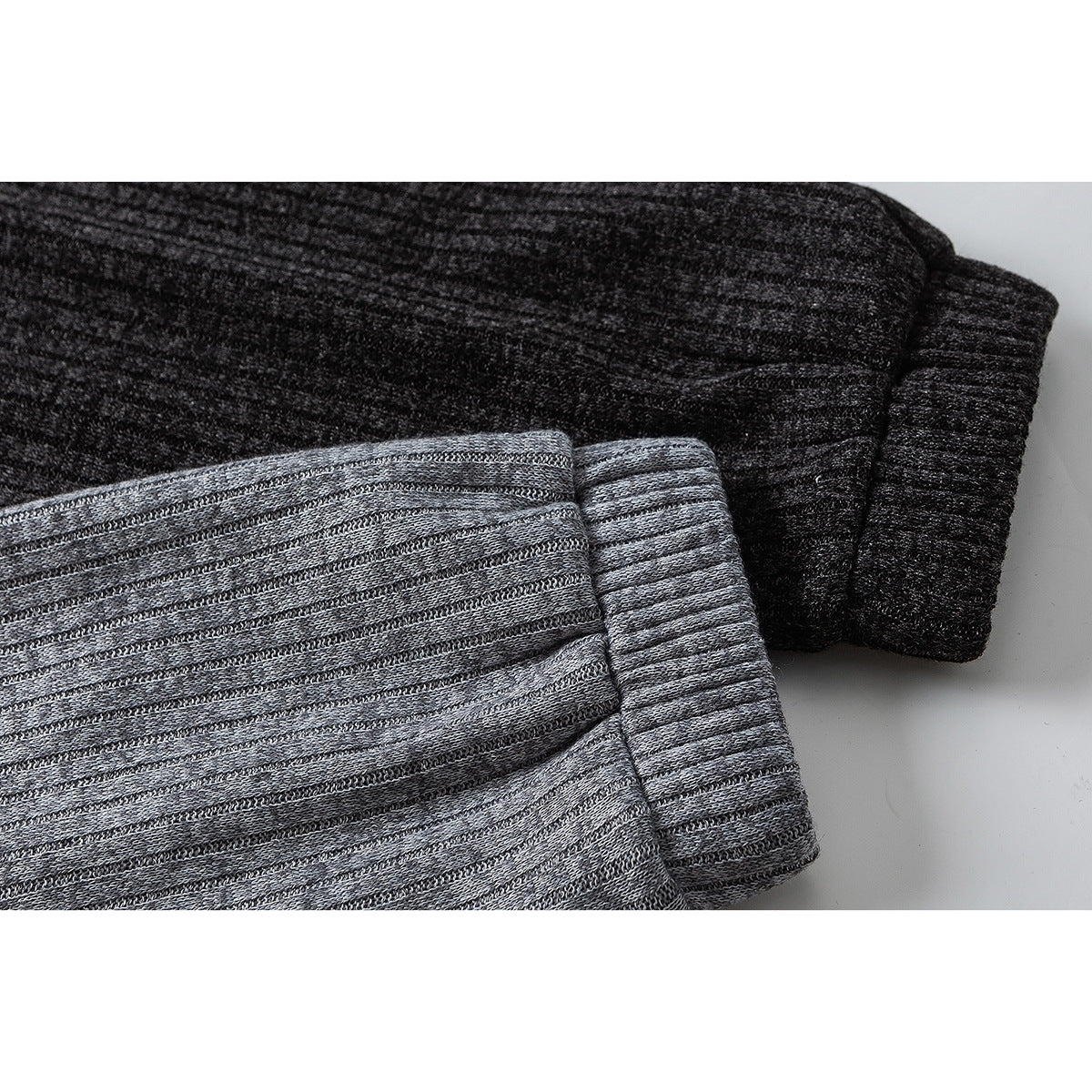 Close-up of folded sleeve cuffs in charcoal and gray ribbed fabric.