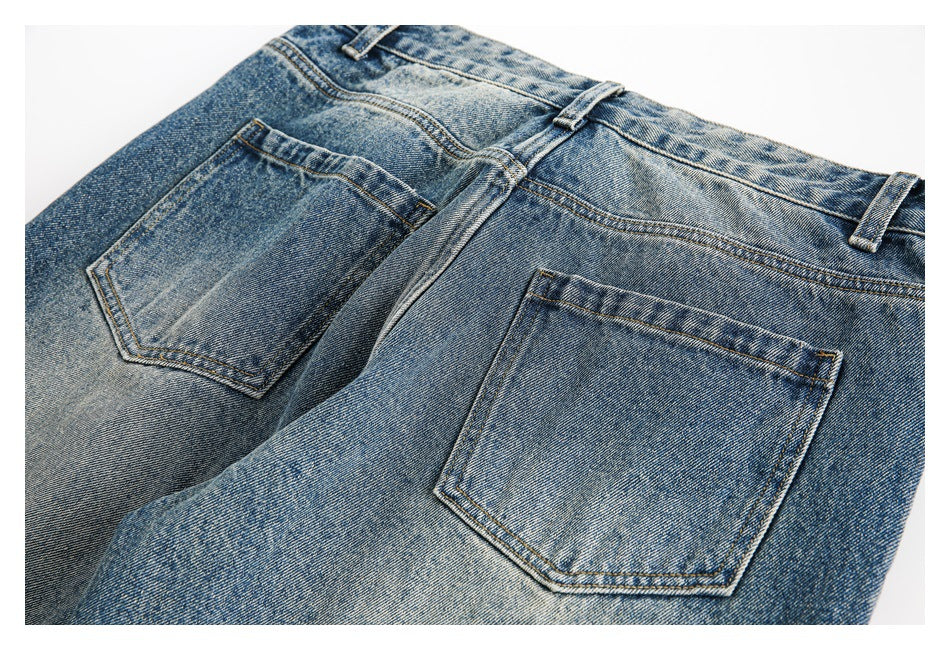 Close-up of the back of blue jeans, showing two patch pockets, belt loops, and contrast stitching.
