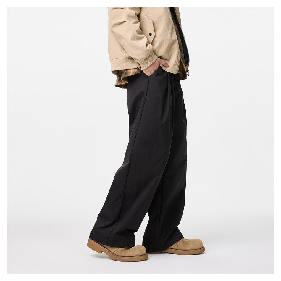 Cropped model wearing loose black wide-leg trousers with a beige jacket, shown from a side-front angle.