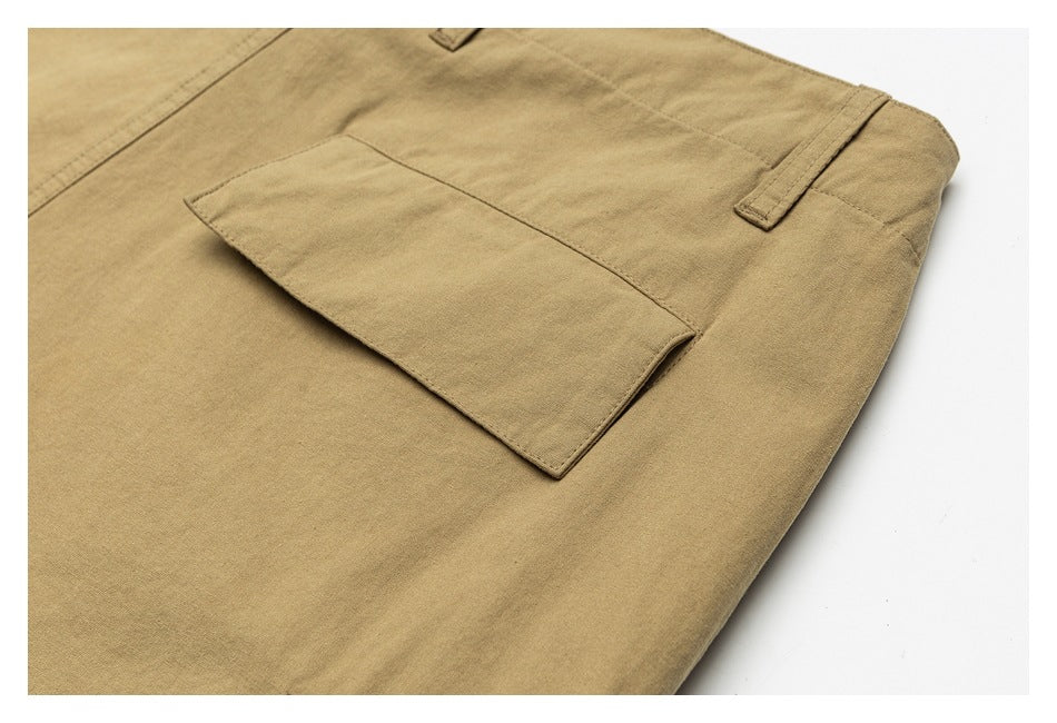 Angled close-up of a rectangular flap pocket and belt loop on tan trousers.