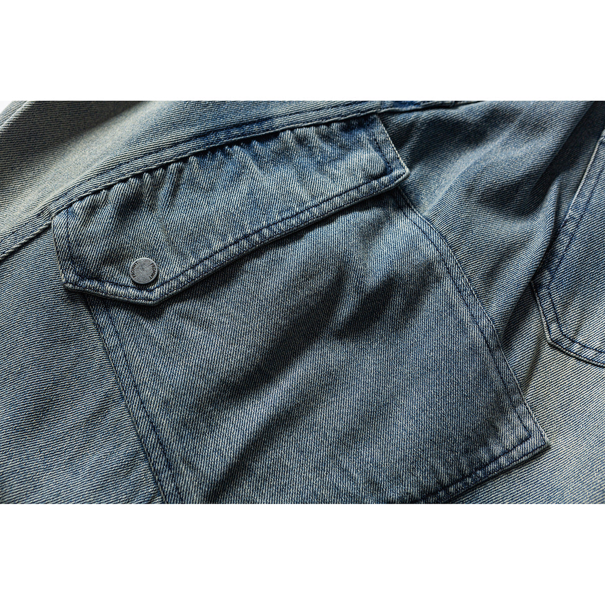 Close-up of a blue denim cargo pocket with a flap and small button.