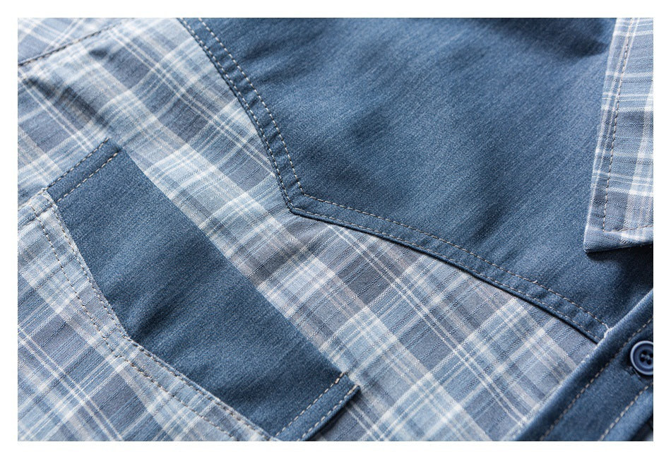 Close-up of a blue denim shirt panel bordered by gray-blue plaid fabric and visible stitching.