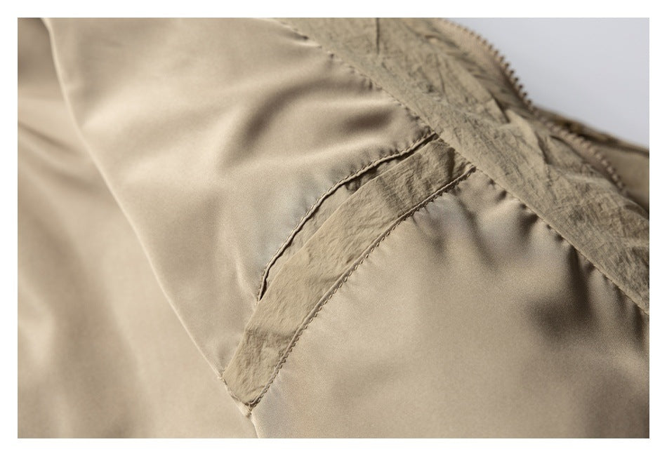 Close-up of the beige jacket's smooth inner panel and stitched seam near the zipper edge.