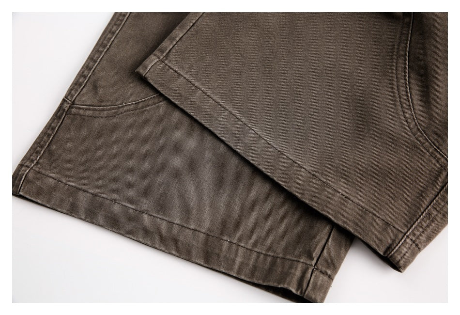Close-up of overlapping brown trouser legs, showing the hems and curved stitching.