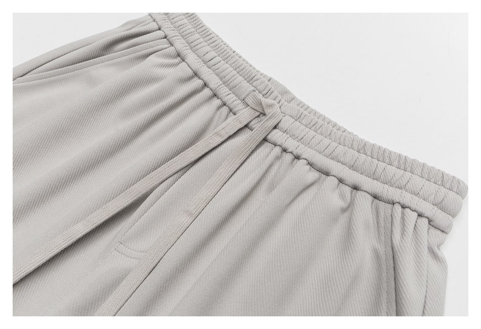 Close-up of the light gray shorts' elastic waistband, tied drawstring, and gathered fabric.