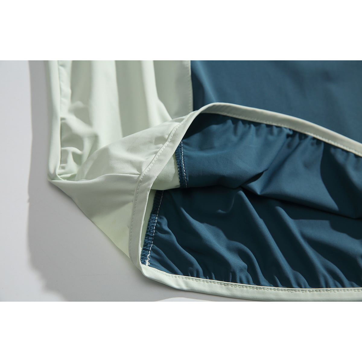 Close-up of the pullover's interior and pale bound seam, showing teal fabric and stitching.