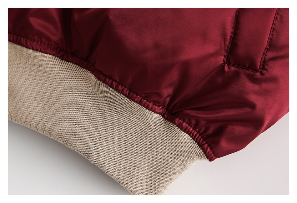 Close-up of a burgundy jacket hem with beige ribbed trim and stitched seams.