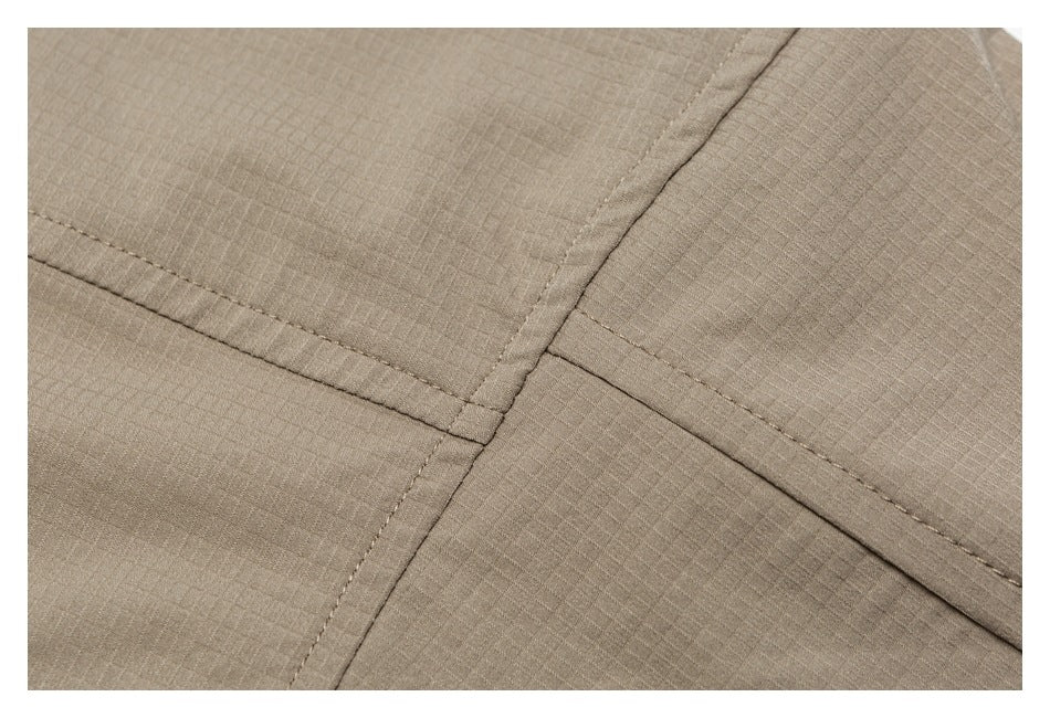 Close-up of intersecting stitched seams on taupe grid-textured fabric.