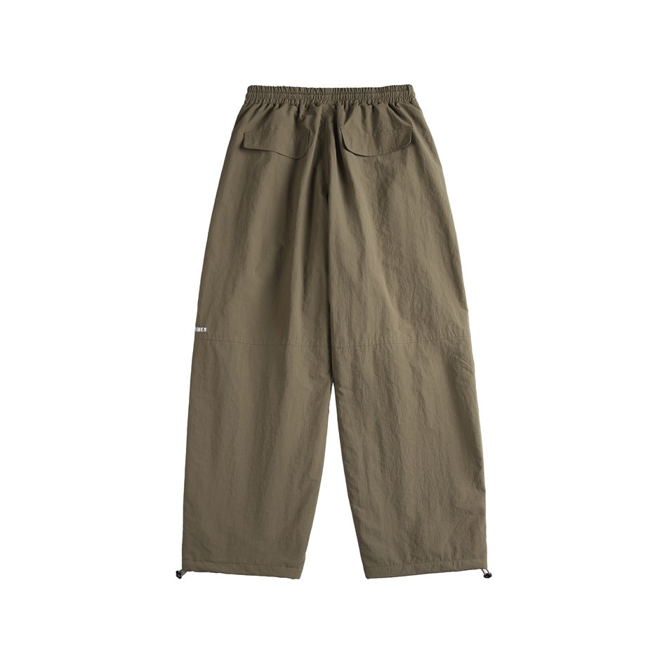 Full rear view of olive-brown wide-leg pants with an elastic waist, two flap pockets, and adjustable cuffs.