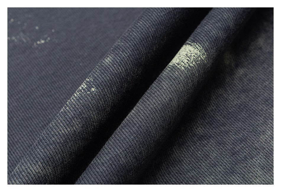 Close-up of dark charcoal fabric with a pale speckled abstract print and visible folds.