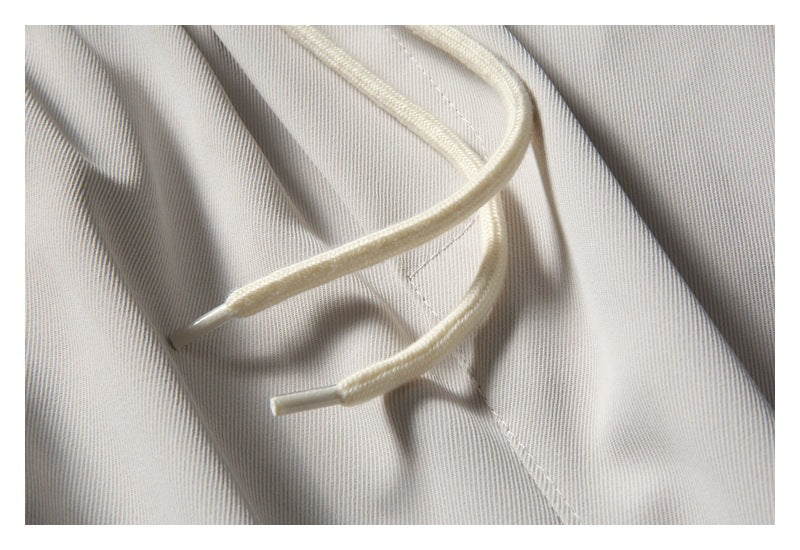 Close-up of the cream drawstring, stitching, and fine texture of the light gray pants.