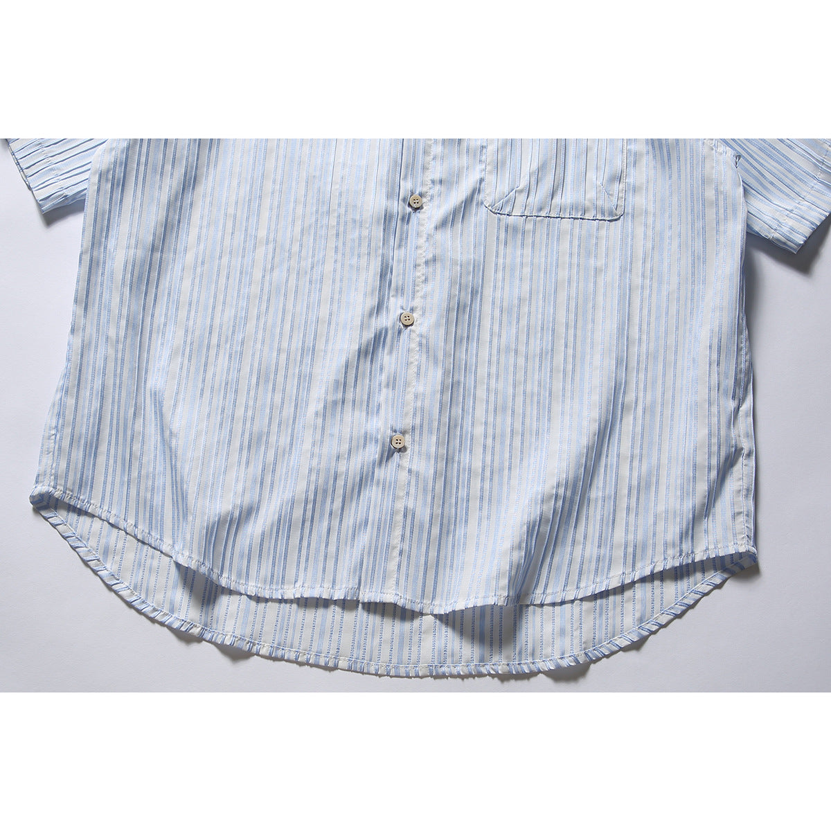 Cropped flat lay of a white short-sleeve button-up shirt with pale blue stripes and a chest pocket.