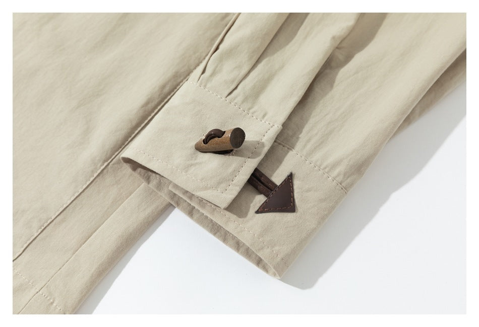 Close-up of a beige sleeve cuff with a brown wooden toggle and triangular patch detail.