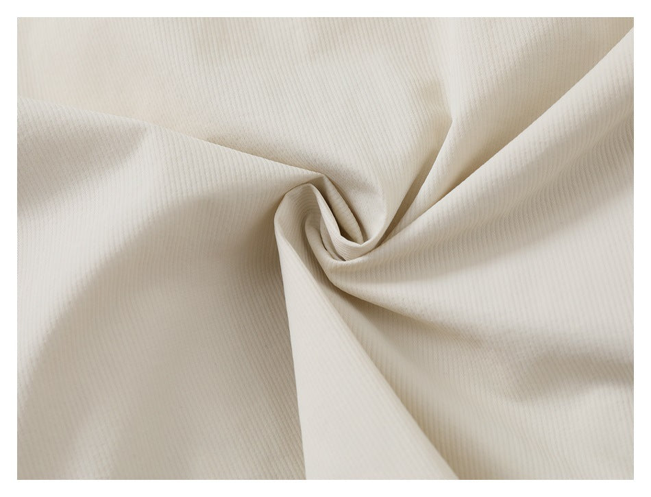 Close-up of ivory ribbed fabric gathered into a swirl to show its texture.