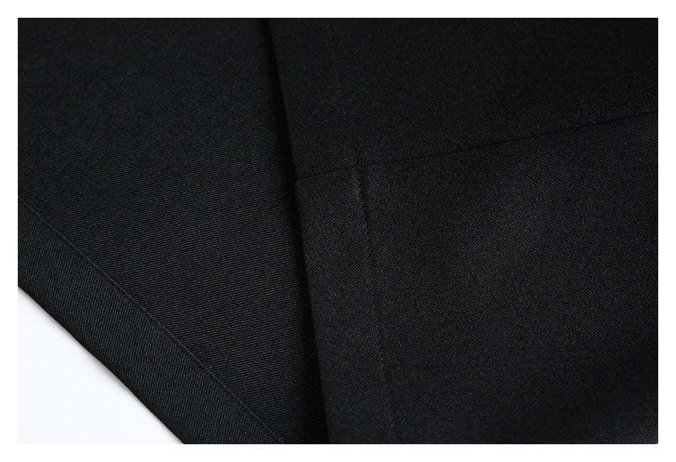 Close-up of black garment fabric showing stitched panel seams and the hem edge.