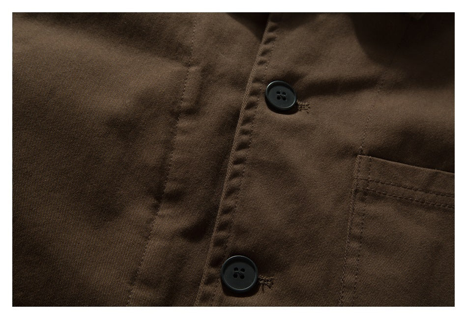 Close-up of the dark brown shirt front with two black buttons and part of a chest pocket.
