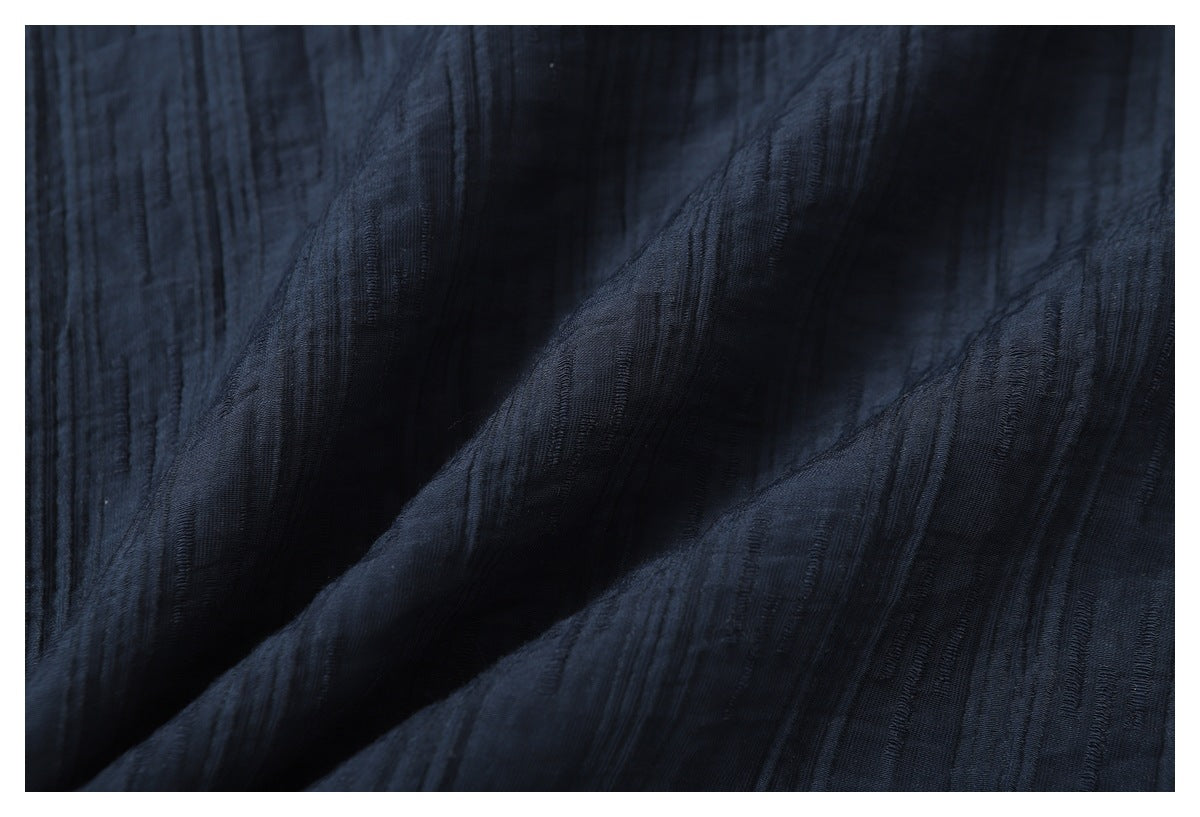 Close-up of the dark navy garment's raised, irregular linear texture across softly folded fabric.