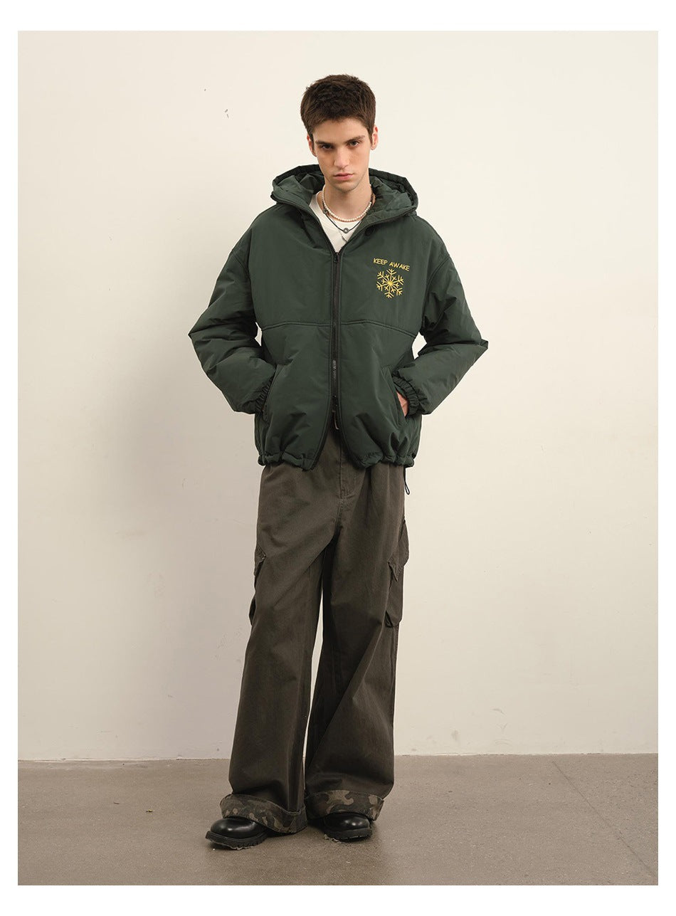 Full-length front view of a model wearing a dark green hooded zip jacket with yellow chest embroidery.