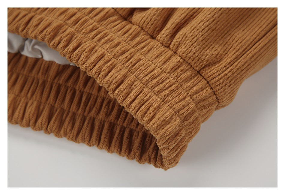 Close-up of a gathered edge and ribbed texture on a caramel-brown garment.