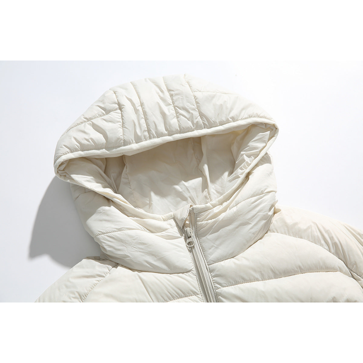 Close-up of an ivory quilted puffer jacket hood and front zipper.