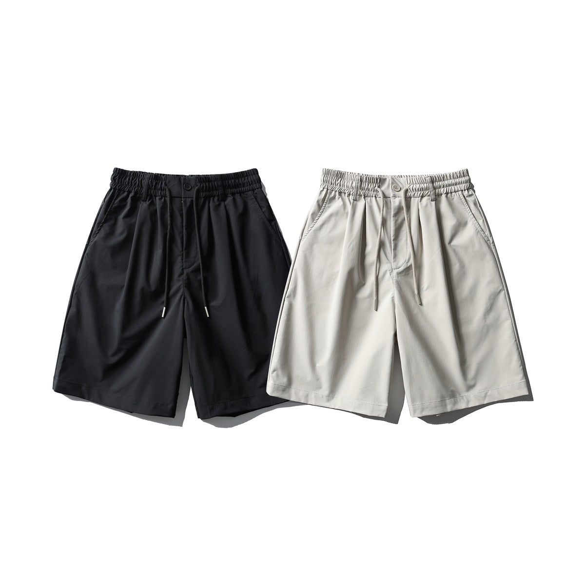 Front view of pleated shorts with elastic waistbands and drawstrings in black and light beige.
