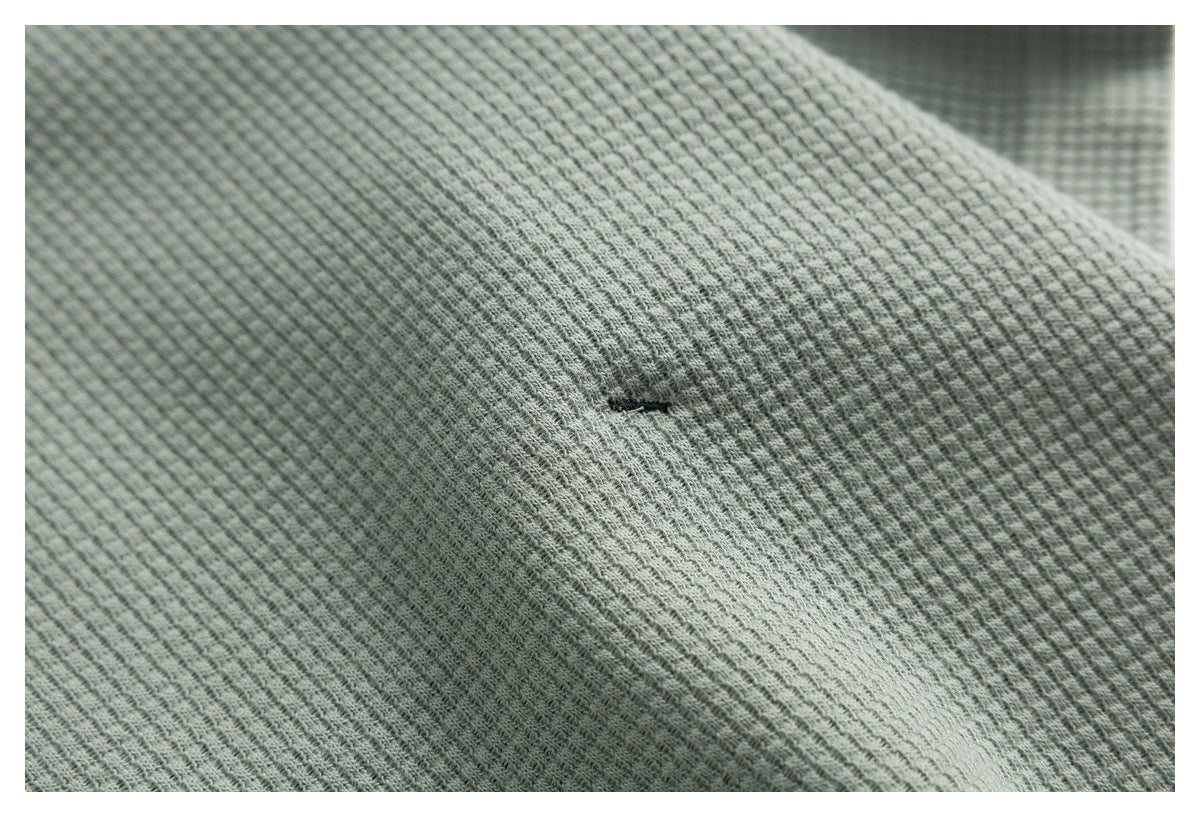 Close-up of the sage green top's textured fabric and a small stitched opening.