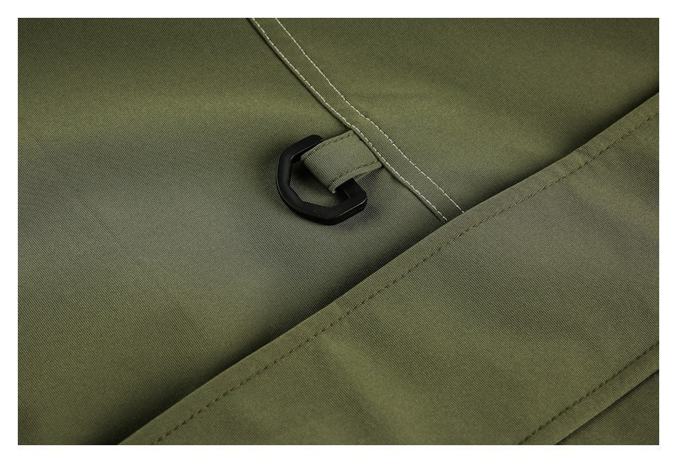 Close-up of an olive garment with a black D-ring loop and stitched belt tab.