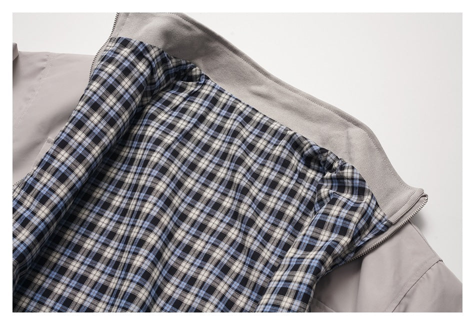 Close-up of a light taupe jacket opened to show its blue, black, and cream plaid lining.