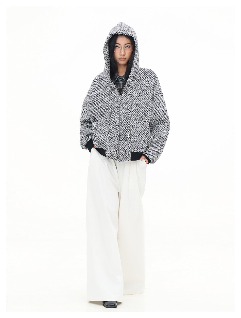 Full-length front view of a model wearing a black-and-white patterned hooded jacket and wide-leg white trousers.