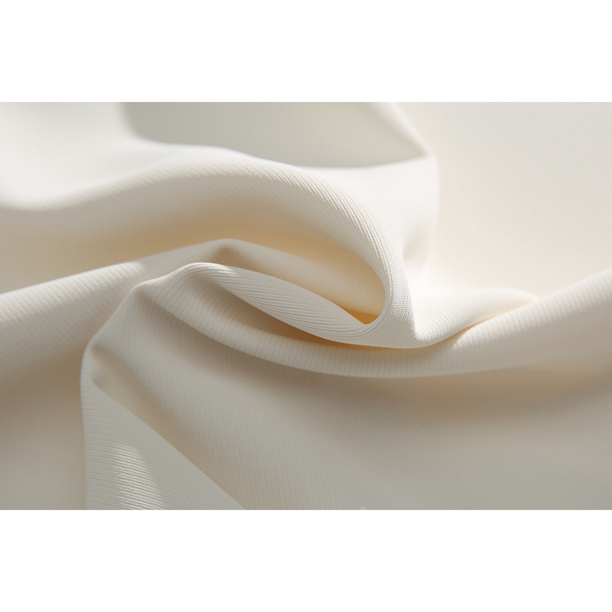 Macro view of ivory garment fabric folded to show its fine textured surface.