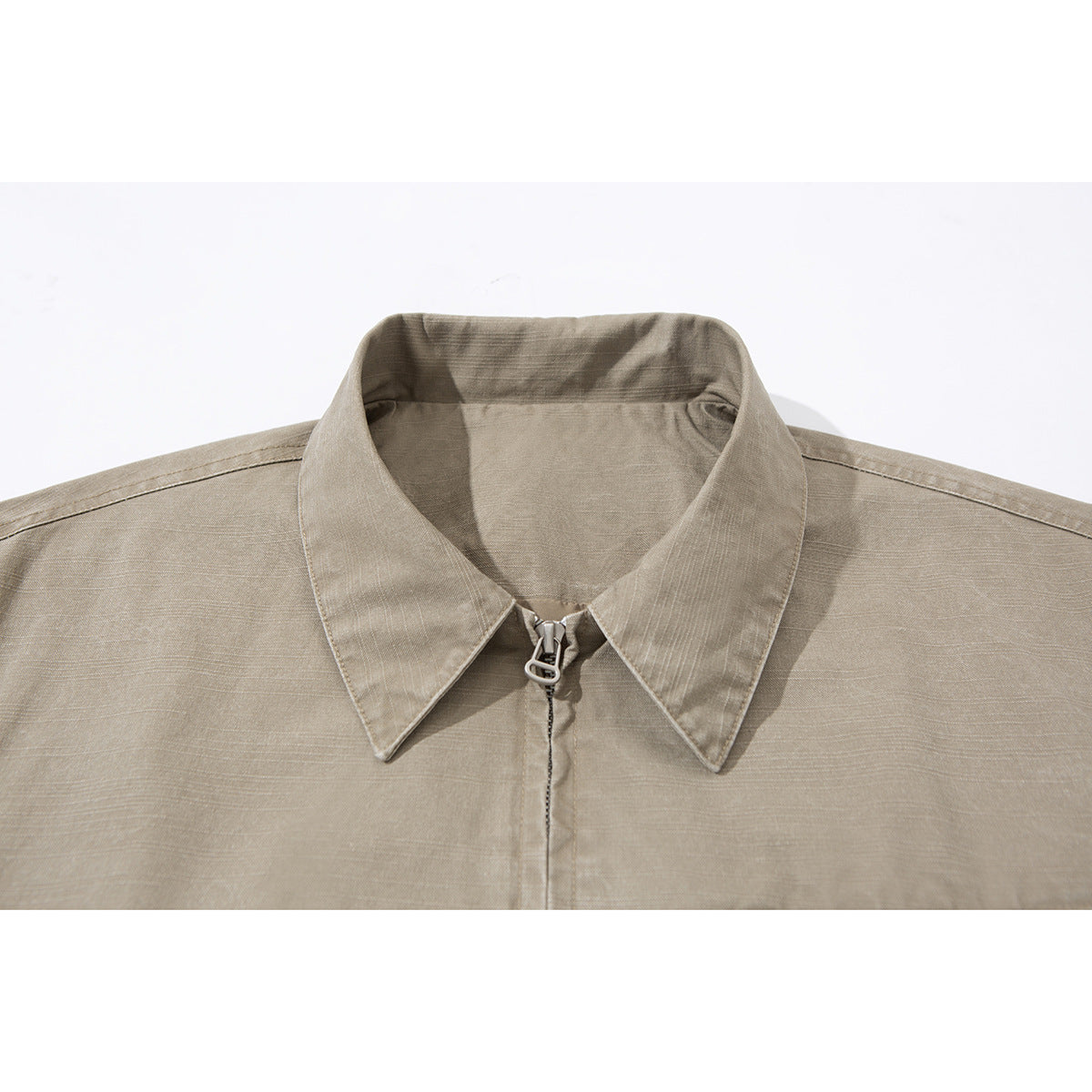 Close-up of a taupe jacket collar and front zipper with a metal pull.