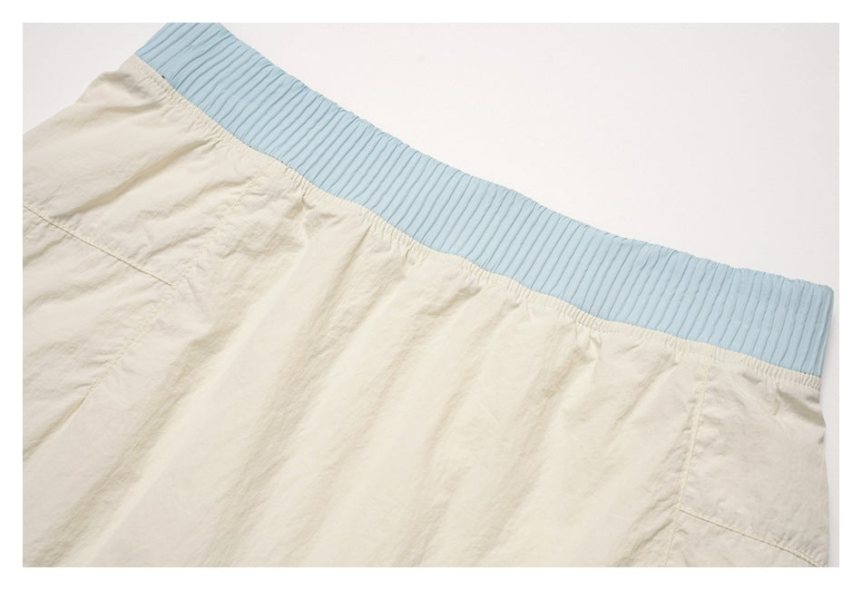 Close-up of the gathered cream skirt body beneath its wide ribbed light-blue waistband.