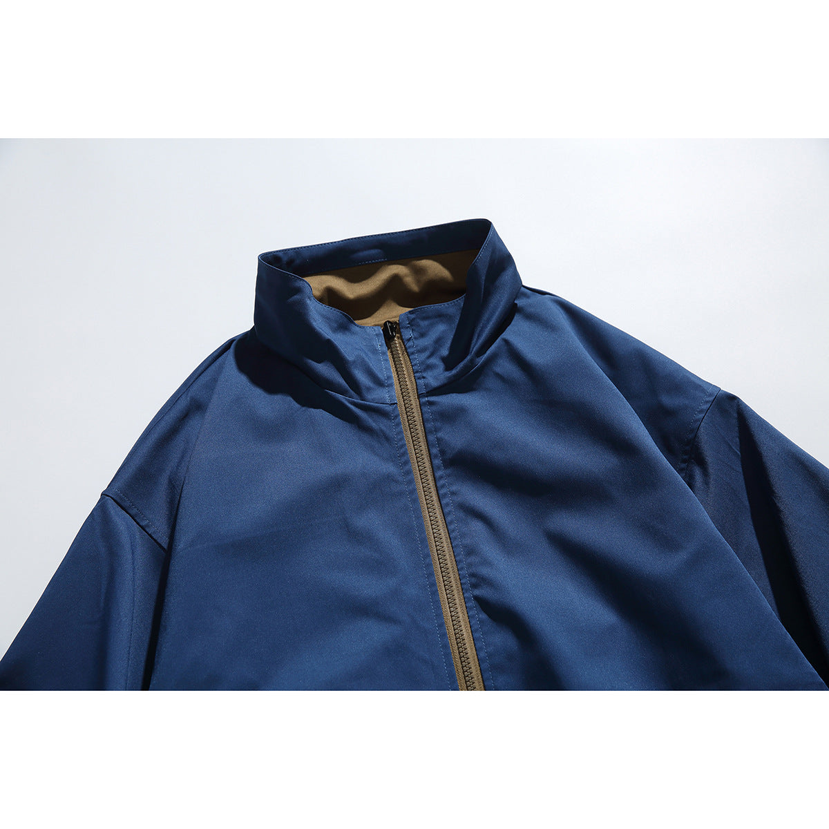 Close-up of a navy jacket’s raised collar and brown front zipper.