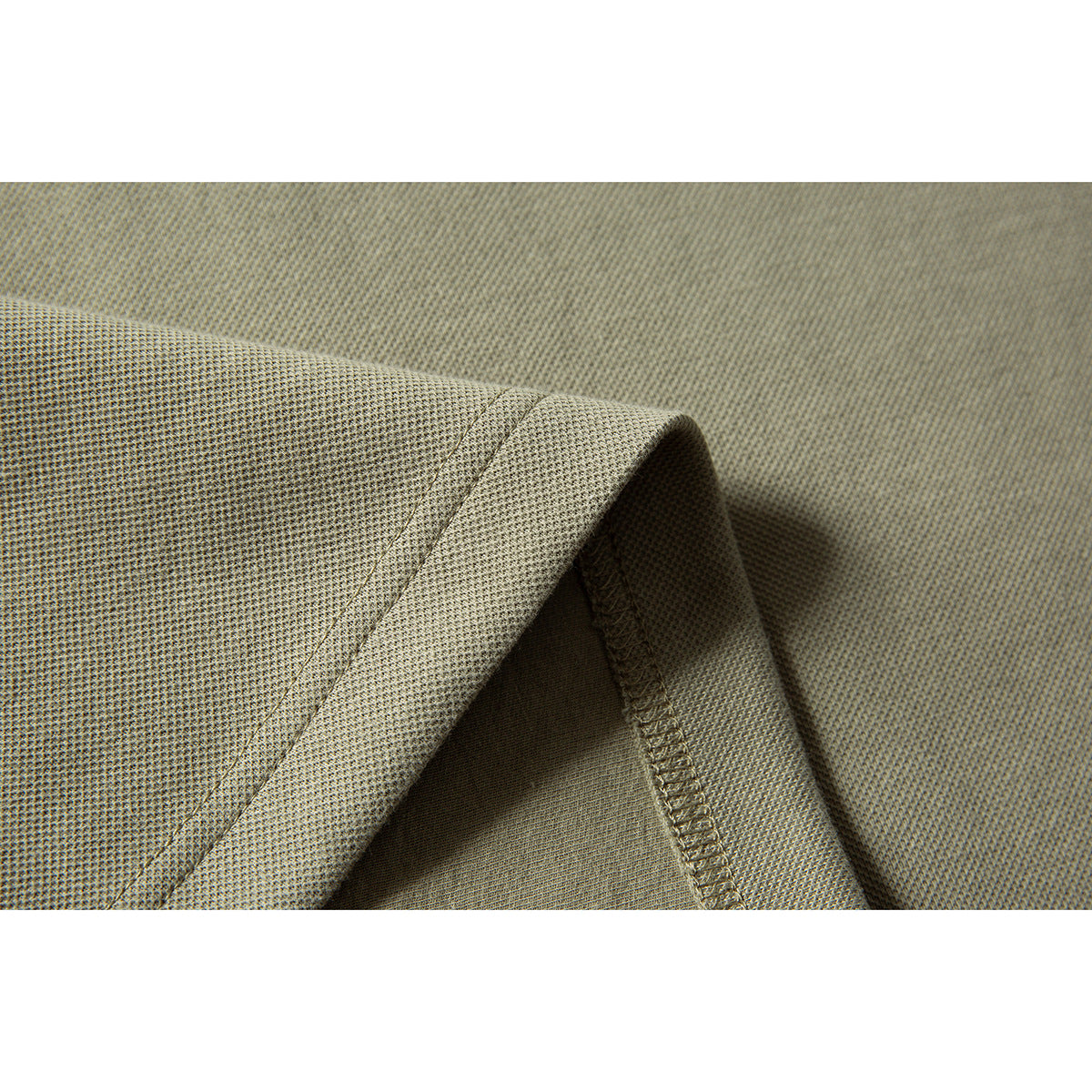 Close-up of a khaki garment’s textured fabric and folded edge with visible overlock stitching.