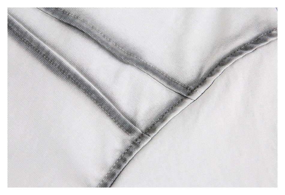 Close-up of intersecting dark-stitched seams on light-colored shirt fabric.