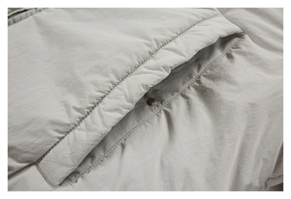 Close-up of a quilted flap pocket with a snap on a light gray-beige jacket.