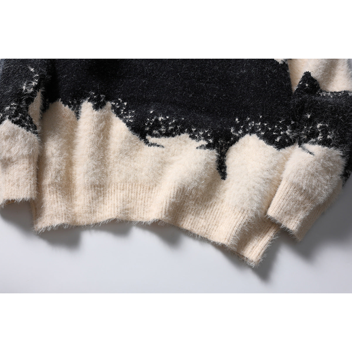 Close-up of the cardigan's ivory ribbed hem and cuffs beneath its black and ivory abstract pattern.