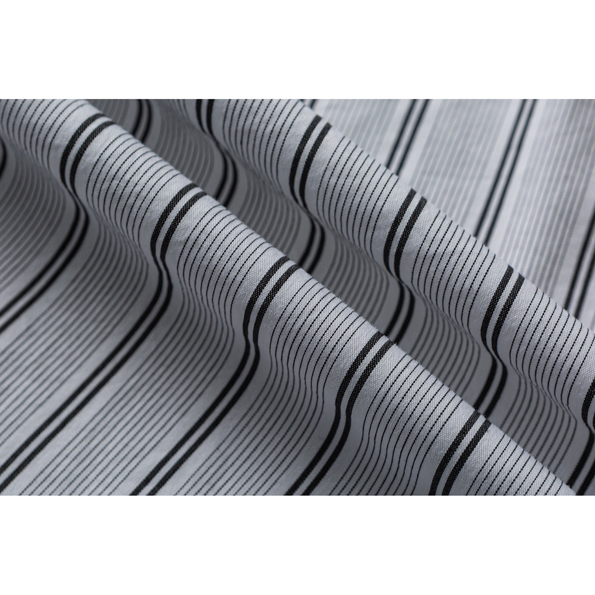 Close-up of white fabric with fine black stripes and alternating thicker black lines, draped in folds.