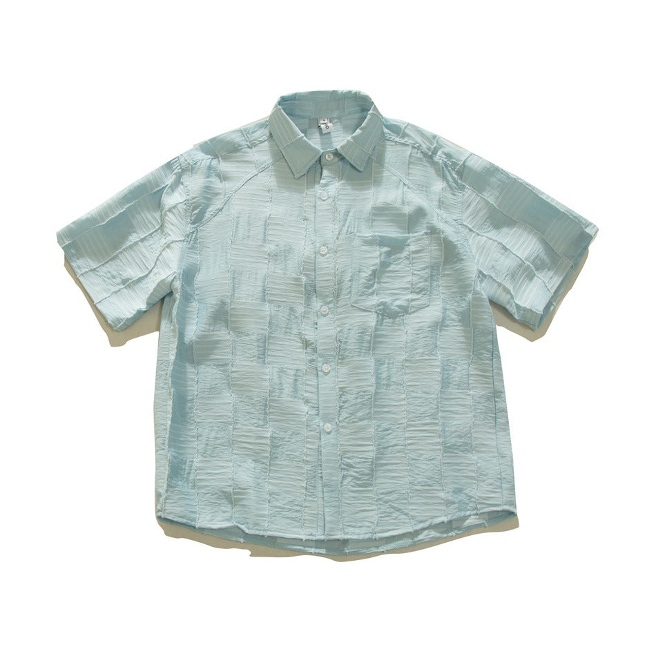 Light blue short-sleeve button-up shirt with crinkled checkered patchwork texture and chest pocket, flat lay front view