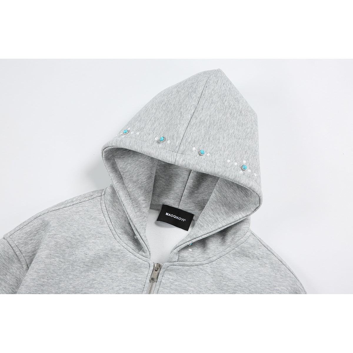 Close-up of a light gray zip-up hoodie hood with turquoise and white embellishments along the edge.