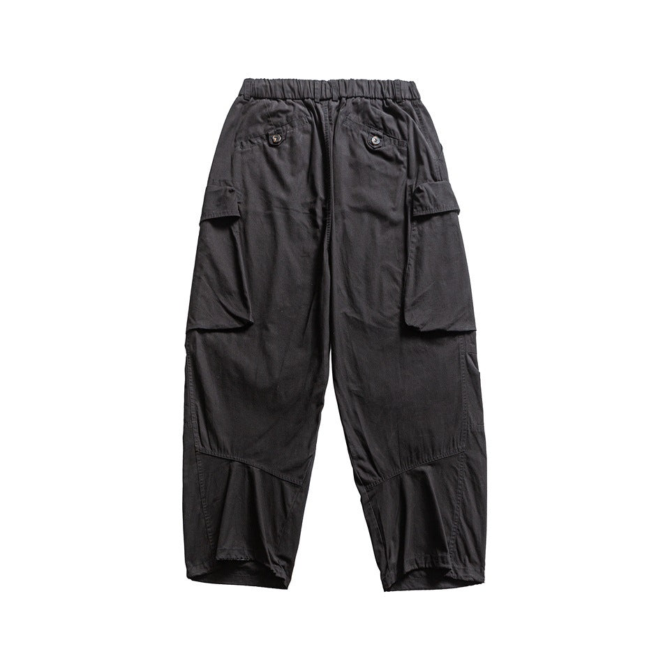 Back view of dark charcoal cargo pants with an elastic waist, buttoned back pockets, large flap pockets and paneled legs.
