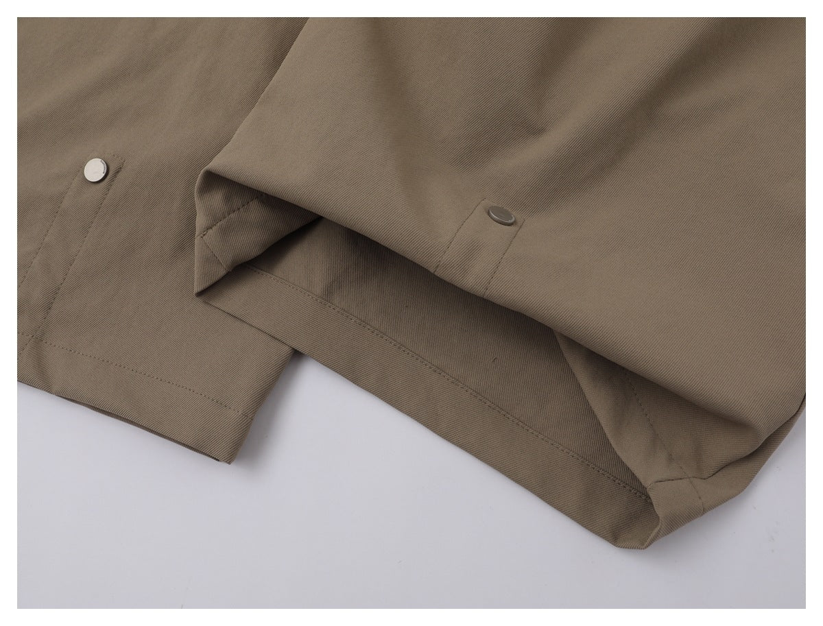 Close-up of taupe fabric with stitched seams, a folded hem, and two round snap buttons.