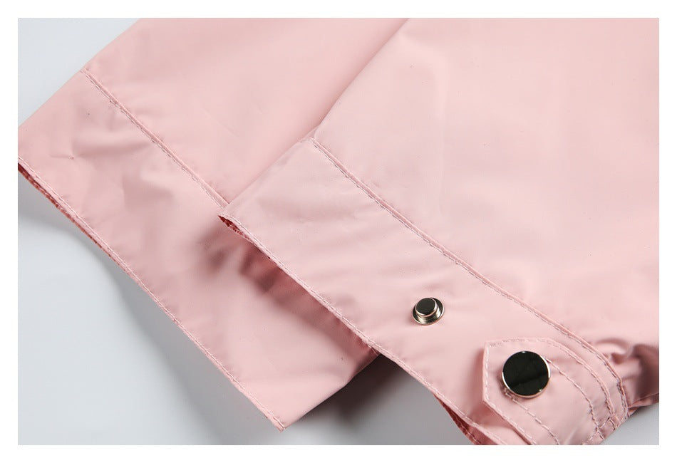 Close-up of a pale pink garment cuff or flap with a metal snap and matching stitched tab.