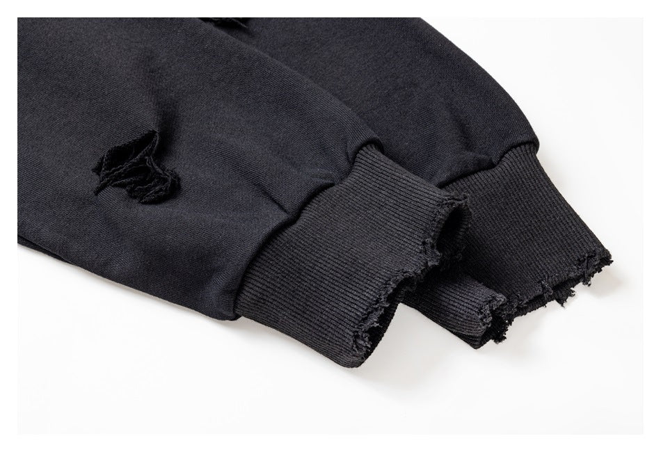 Close-up of a black sleeve with a ribbed, distressed cuff and a small frayed tear.