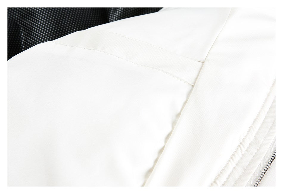 Close-up of a white garment showing a curved stitched seam and zipper beside black dotted lining.