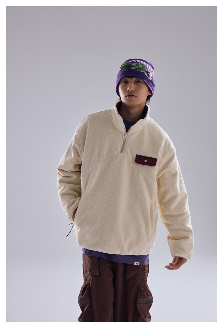 Model wearing an ivory quarter-zip pullover with a burgundy chest pocket and a raised collar.