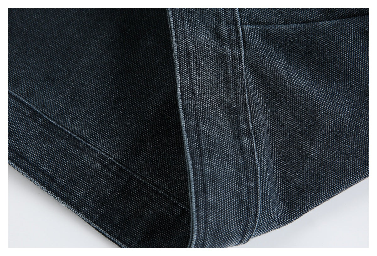 Close-up of dark textured denim seams and a folded, stitched garment edge.