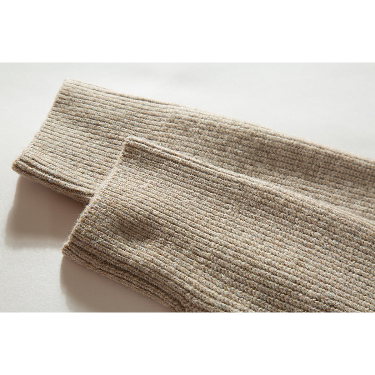 Close-up of two beige rib-knit sweater cuffs and their textured edges.
