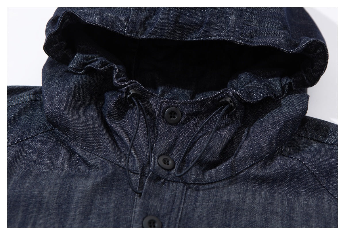 Close-up of a dark indigo hooded jacket's gathered hood edge, drawcords, and buttoned neckline.